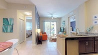 This single-floor residence offers a well-designed, open layout that connects the kitchen, dining, and living areas into a cohesive, light-filled space. Large-format tile flooring runs throughout the main living areas, contributing to a clean, airy aesthetic.

The kitchen is outfitted with dark espresso cabinetry extending to the ceiling, stainless steel appliances including a refrigerator, electric range, and microwave, and granite countertops that continue onto a raised breakfast bar. This peninsula-style counter serves as a natural divider between the kitchen and the living area.

The living room features a bold accent wall in slate gray, a ceiling fan, and a sliding glass door that opens to a private patio with greenery views, allowing ample natural light to fill the space.

Two bedrooms are carpeted and comfortably scaled, each with ceiling fans and generous closet space. The primary bedroom connects directly to the full bathroom, which includes dark wood vanity cabinetry, granite countertops, a soaking tub with tile surround, and large-format tile flooring. A second full bathroom is also accessible from the hallway.