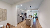 Located at 1588 Bloom St in Mount Pleasant, South Carolina, this single-floor residence offers a thoughtfully designed open-concept layout with contemporary finishes throughout. The kitchen serves as the heart of the home, featuring sleek gray shaker cabinetry, stainless steel appliances including a gas range and built-in microwave, a subway tile backsplash, and a central island with a granite countertop and undermount sink — ideal for both cooking and casual dining. Warm-toned hardwood flooring extends seamlessly from the kitchen through the living and dining areas, creating a cohesive, inviting flow. The dining area provides an intimate setting with clean white walls and ample space for a round table. The living room is bright and welcoming, benefiting from natural light and direct access to a glass door entrance. The bedrooms offer a calm retreat, each with plush carpeting, ceiling fans, and generous natural light from well-placed windows. The bathroom is elegantly appointed with granite countertops, white cabinetry, a large mirror, and a glass-enclosed walk-in shower. A dedicated laundry room with a full-size washer and dryer completes the practical amenities of this well-rounded Mount Pleasant residence.