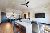 Located at 426 S Tejon St in the heart of Colorado Springs, this contemporary 2-bedroom, 2-bathroom residence offers a thoughtfully designed open-concept layout finished with warm hardwood-style flooring and a clean, modern aesthetic throughout. The combined kitchen and living area forms the centerpiece of the home, where a sleek kitchen features dark cabinetry, stainless steel appliances, a decorative patterned tile backsplash, and a large island with bar seating illuminated by stylish pendant lighting. The living area flows seamlessly from the kitchen, bathed in abundant natural light from expansive floor-to-ceiling windows that frame open city views and are fitted with dark roller shades. A ceiling fan adds comfort overhead. Built-in shelving provides functional display space along the living room walls. Both bedrooms are well-proportioned and serene, with the primary suite offering direct access to an en-suite bathroom complete with dark cabinetry, gold hardware, and a glass-enclosed walk-in shower. The second bathroom features a full tub-shower combination. Two hallways connect the space efficiently, with one offering coat hooks and louvered closet doors. The overall ambiance is urban and refined, blending modern finishes with a warm, livable character.