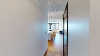 Located at The Victor in St. Louis, Missouri, this one-bedroom, one-bathroom residence showcases a thoughtfully designed open-concept layout with distinct industrial-modern character. Soaring ceilings with exposed ductwork and structural beams lend an authentic loft aesthetic throughout, while warm hardwood flooring flows continuously across the entire space.

The kitchen serves as a central hub, featuring white shaker cabinetry, a tile backsplash, stainless steel appliances, and a generous island with seating for multiple guests. Pendant lighting illuminates the island and transitions naturally into the open living area, where large, dark-framed windows frame city views and flood the space with natural light. A dedicated flex area near the windows provides an ideal setting for a home office or reading nook.

The bedroom is a calm retreat with elevated ceilings, ample wall space, and direct access to the bathroom. A sliding barn door adds an architectural accent connecting areas of the unit. The bathroom features a long, white quartz vanity with a dark-framed mirror, wood-toned cabinetry, hardwood flooring, and a glass-enclosed walk-in shower with vertical tile detailing. The overall ambiance is bright, airy, and refined.