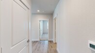This well-appointed single-floor home offers a thoughtfully designed layout with 2 bedrooms, 2 bathrooms, and 2 closets. The open-concept kitchen and living area serves as the heart of the home, featuring a large center island with a granite countertop and undermount sink, sleek white cabinetry extending to the ceiling, a subway tile backsplash, and a full suite of stainless steel appliances including a refrigerator with ice maker, electric range, and built-in microwave. Recessed lighting and light hardwood-style flooring flow throughout the main living areas, creating a bright and cohesive aesthetic. The spacious living room is filled with natural light from multiple windows offering outdoor views, complemented by a ceiling fan with light fixture. Both bedrooms feature plush carpet flooring and ceiling fans, with the primary bedroom offering a generous footprint. The two bathrooms are well-finished, with one showcasing a full-length vanity topped with granite, a large wall mirror, a tub/shower combination with marble-style tile surround, and hardwood-style flooring. A central hallway with recessed lighting connects all areas of the home, maintaining a clean, neutral palette of soft whites and grays throughout.