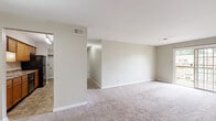 Located at 1420 King Arthur Court in Evansville, Indiana, this single-story unit offers a straightforward, functional layout designed for comfortable everyday living. The interior is finished with neutral, light-toned walls throughout, creating a bright and cohesive atmosphere across all rooms.

The main living area is generously sized, featuring wall-to-wall carpeting and an open feel enhanced by a sliding glass door that provides direct access to an outdoor space and allows natural light to flow in. A built-in closet with bifold doors in this area adds convenient storage. An adjoining room — visible through a connecting opening — extends the usable living space and is similarly finished with carpet and neutral walls.

The galley-style kitchen is well-equipped with warm wood cabinetry, stone-patterned laminate countertops, and a full suite of black appliances including a refrigerator, dishwasher, and range. Tile flooring runs throughout the kitchen, and a utility area with shelving is accessible directly from this space.

The bedrooms are carpeted and offer ample room, with one featuring a wide bifold-door closet with a full hanging rod and overhead shelf. Additional bedrooms include their own closet access and multiple electrical outlets.

The bathroom is clean and functional, featuring a tub-shower combination, a single-sink vanity with a wood cabinet base, tile flooring, and a large wall mirror with chrome fixtures throughout.