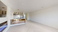 Located at 4336 Mission Rd in Kansas City, Kansas, this single-floor space offers a thoughtfully designed open-concept layout with a clean, modern aesthetic. The interior is defined by striking light-toned herringbone flooring that flows seamlessly throughout the living areas, complemented by crisp white walls and recessed lighting that create a bright, airy atmosphere.

The kitchen serves as a centerpiece, featuring a large island topped with a dramatic white marble-veined countertop and an integrated cooktop. Warm wood cabinetry with glass-front uppers, brushed gold hardware, a mosaic tile backsplash, and a gold-finish faucet add refined detail. Stainless steel appliances, including a refrigerator and built-in microwave, complete the functional design. A sculptural gold ring pendant light adds a striking focal point above the island, alongside open gold wall-mounted shelves.

The expansive open living area provides generous space and benefits from natural light through a large window, with a modern front entry door offering additional light. The bathroom is appointed with full marble-look tile, a walk-in glass shower with hexagonal mosaic floor tile and gold fixtures, and a conveniently integrated laundry closet. Every detail in this space reflects a cohesive, contemporary design with luxurious gold accents throughout.