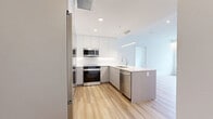 Located at Ferry Wharf Road in Kelowna, BC, this well-appointed 3-bedroom, 2-bathroom unit offers a thoughtfully designed single-level layout with a clean, modern aesthetic throughout. The open-concept kitchen is a standout feature, showcasing flat-panel white cabinetry extending to the ceiling, light quartz countertops, a peninsula with an undermount sink, and stainless steel appliances including a full-size refrigerator, range, and built-in microwave. Pendant lighting and recessed pot lights add a polished finishing touch. Light wood-look flooring flows seamlessly through the living areas and bedrooms, creating a warm yet contemporary feel. The bedrooms are bright and airy, each benefiting from large windows that invite natural light and offer views of the surrounding neighbourhood. The primary bedroom provides a comfortable, well-proportioned retreat. Both bathrooms are finished with large-format marble-look porcelain tile on floors and walls, glass-enclosed showers, soaker tub, and modern vanities with backlit mirrors, lending a spa-like quality to the space. Clean white walls and sleek chrome hardware are consistent throughout, contributing to the unit's cohesive and contemporary character.