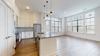 Located at 4220 Colony Plaza Dr in Charlotte, NC, this thoughtfully designed single-floor residence offers a bright, open layout filled with natural light from large, decorative-trimmed windows throughout. The open-concept kitchen and living area forms the heart of the home, anchored by a central island with granite countertops and a built-in sink, pendant lighting overhead, and crisp white shaker cabinetry with a herringbone tile backsplash. Stainless steel appliances, including a full-size refrigerator and microwave, complete the well-appointed kitchen. Rich hardwood-style flooring flows through the main living areas, adding warmth and continuity to the space. The primary bathroom features a dual-sink vanity with granite countertops, bold navy-blue cabinetry, large-format tile flooring, and a glass-enclosed walk-in shower. A secondary bathroom mirrors the refined aesthetic with granite countertops, subway tile surrounding a soaking tub, and light tile flooring. The bedrooms are carpeted for comfort, with generous dimensions, high ceilings, and ample natural light from sizable windows. Select bedrooms include walk-in closets and direct bathroom access, enhancing both privacy and convenience throughout this well-crafted Charlotte residence.