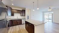 Located at 2505 S George St in York, PA, this well-appointed one-bedroom, one-bathroom residence offers a thoughtfully designed single-floor layout. The open-concept kitchen and living area serves as the heart of the home, featuring rich dark-brown cabinetry, granite countertops, a central island with pendant lighting, and a full suite of stainless steel appliances including a refrigerator, range, microwave, and dishwasher. Light hardwood-style flooring flows throughout the main living areas, complementing the neutral color palette and creating a bright, cohesive feel. The living room is bathed in natural light through large sliding glass doors that open to the outside, and a ceiling fan adds comfort overhead. The bedroom is a comfortable retreat with plush carpeting, a ceiling fan, and a window that lets in natural light. A spacious walk-in closet with wire shelving provides ample storage. The bathroom mirrors the home's refined aesthetic with a granite-topped vanity, dark cabinetry, and a full soaking tub with shower. A dedicated laundry area houses a stacked Whirlpool washer and dryer unit alongside built-in shelving, adding everyday convenience to this well-rounded residence.