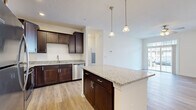 Located at 2505 S George St in York, PA, this well-appointed one-bedroom, one-bathroom residence offers a thoughtfully designed single-floor layout. The open-concept kitchen and living area serves as the heart of the home, featuring rich dark-brown cabinetry, granite countertops, a central island with pendant lighting, and a full suite of stainless steel appliances including a refrigerator, range, microwave, and dishwasher. Light hardwood-style flooring flows throughout the main living areas, complementing the neutral color palette and creating a bright, cohesive feel. The living room is bathed in natural light through large sliding glass doors that open to the outside, and a ceiling fan adds comfort overhead. The bedroom is a comfortable retreat with plush carpeting, a ceiling fan, and a window that lets in natural light. A spacious walk-in closet with wire shelving provides ample storage. The bathroom mirrors the home's refined aesthetic with a granite-topped vanity, dark cabinetry, and a full soaking tub with shower. A dedicated laundry area houses a stacked Whirlpool washer and dryer unit alongside built-in shelving, adding everyday convenience to this well-rounded residence.
