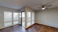 Located at 380–384 Glenwood Circle in Monterey, California, this single-floor residence offers a well-organized layout with a cohesive, neutral aesthetic throughout. Rich, dark wood-style flooring runs continuously across the living areas and bedrooms, providing a warm contrast to the soft gray walls and white trim found throughout the space.

The living room is a standout area, featuring a classic fireplace as a focal point, a ceiling fan, and an abundance of natural light streaming through large windows fitted with horizontal blinds. A sliding glass door leads to a private balcony, extending the living space outdoors and allowing views of surrounding greenery.

The kitchen is thoughtfully designed with crisp white cabinetry, dark granite-style countertops, and black appliances including an electric range with an overhead ventilation hood. A pass-through counter connects the kitchen to the main living and dining area, supporting an open, functional flow.

The bedroom is a quiet, well-proportioned room with a window overlooking outdoor greenery, baseboard heating, and the same warm wood-style flooring. The bathroom features a clean, white finish with a tub-shower combination, white vanity cabinetry, and matching dark countertops that tie back to the kitchen's design language.

Overall, the space presents a clean, updated interior with consistent finishes throughout.