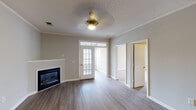 Located at 750 Boone Station Dr in Burlington, NC, this single-floor residence offers a well-designed layout with a variety of functional living spaces. The living room serves as the heart of the home, featuring rich hardwood-style flooring, crown molding, a textured ceiling, a ceiling fan, and a sleek corner fireplace that adds warmth and character. French-style doors connect the living area to a bright sunroom or flex space, where large windows invite generous natural light and outdoor views. An adjacent dining or secondary living area continues the hardwood-style flooring and provides a seamless flow toward the kitchen. The kitchen is equipped with white cabinetry, granite-style countertops, a full suite of stainless steel appliances including a refrigerator, range, microwave, and dishwasher, along with track lighting and light wood-style flooring. The bedrooms are carpeted and comfortably sized, each with ceiling fans and ample wall space. The bathrooms are finished with wood-style flooring, white cabinetry with granite-style countertops, and tub-shower combinations. Throughout the home, neutral gray walls and white trim create a clean, cohesive aesthetic suited to a variety of interior styles.
