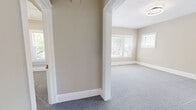Located at 3845 Riveredge Rd, Unit 8 in Cleveland, OH, this 530-square-foot single-floor apartment offers 2 bedrooms, 1 bathroom, a kitchen, and two hallways. The unit features a neutral warm beige color palette throughout, creating a cohesive and welcoming ambiance. Both bedrooms are carpeted with soft gray carpet and receive natural light through white-framed windows. The primary bedroom, at 210 square feet, includes crown molding and a built-in closet with open shelving. The secondary bedroom also features crown molding, a window with natural views, and ample wall space. The kitchen is well-appointed with white cabinetry, matte black hardware, light quartz countertops, a stainless steel sink, and stainless steel appliances. Light hardwood-style flooring runs through the kitchen, which also includes a built-in shelving nook and dual windows overlooking the exterior. The bathroom showcases large-format marble-look tile surrounding a soaking tub and shower combo with matte black fixtures, complemented by a white vanity with a vessel sink, a framed mirror, and light wood-look flooring. The unit is illuminated by modern flush-mount ceiling light fixtures throughout.