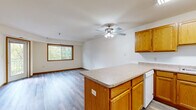 Located at 12555 Pennock Ave in Apple Valley, Minnesota, this 2-bedroom, 2-bathroom single-floor home offers a well-organized and functional layout ideal for comfortable everyday living. The open-concept kitchen and living room serve as the heart of the home, featuring warm oak cabinetry, a central island with ample counter space, white appliances including a refrigerator and range, and hardwood-style flooring that flows throughout the main living areas. A ceiling fan with integrated lighting anchors the living space, which is brightened by a large window with views of surrounding greenery. A glass door leads directly to a private balcony, extending the living space outdoors with pleasant tree-lined views. The primary bedroom is generously sized with natural light streaming through a dedicated window and direct balcony access, while the second bedroom features plush carpeting and its own window overlooking the outdoors. Both bedrooms are supported by four closets throughout the home. The two bathrooms are finished with oak vanities and light countertops; one includes a full tub-shower combination. Hardwood-style flooring carries through the bathrooms and common areas, while carpet adds warmth to both bedrooms. An in-unit laundry area adds everyday convenience, rounding out this well-appointed home.