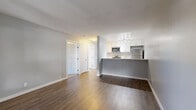 Located at 640 West Lincoln Avenue in Escondido, California, this one-bedroom, one-bathroom residence offers a practical and well-appointed single-floor layout. The open-concept living and kitchen area forms the heart of the home, featuring rich wood-tone laminate flooring, neutral gray walls, and a sliding glass door that fills the space with natural light and provides access to an outdoor patio. The kitchen is efficiently designed with a raised breakfast bar peninsula, crisp white cabinetry, a stainless steel refrigerator, stainless steel microwave, and a stainless steel range, all illuminated by track lighting overhead. The living area offers generous room for furnishings and includes a wall-mounted HVAC unit for year-round comfort. The bedroom is carpeted for warmth and comfort, featuring a window that brings in natural light, and leads directly to a spacious walk-in closet with built-in shelving and hanging rods for ample storage. The bathroom is clean and contemporary, showcasing a white vanity with a marble-style countertop, a full tub-shower combination, wood-look flooring, and brushed nickel fixtures throughout. The overall aesthetic is modern and move-in ready, with a cohesive neutral palette throughout.