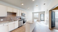 Located near Cahill Pond View in Colorado Springs, CO, this one-bedroom, one-bathroom residence offers a thoughtfully designed single-floor layout with a clean, modern aesthetic. The open-concept kitchen and living area form the heart of the space, featuring light wood-look flooring, recessed lighting, and abundant natural light streaming through large windows with blinds. The kitchen is well-appointed with white shaker-style cabinetry, granite countertops, a tile backsplash, and a full suite of stainless steel appliances, including a refrigerator, range, microwave, and dishwasher. A peninsula provides additional prep and seating space, seamlessly connecting the kitchen to the living area. A glass-panel door in the living room offers access to the outdoors and further brightens the space. The bedroom is carpeted and comfortably sized, complete with a ceiling fan, a natural light-filled window, and distinctive bold blue interior doors that add a pop of character. A dedicated walk-in closet with wire shelving provides ample storage. The bathroom features wood-look flooring, a granite-topped white vanity, and a tiled tub-shower combination, maintaining the cohesive, contemporary style found throughout the residence.