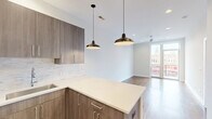 Located in Chicago's vibrant Uptown neighborhood at 5139 North Broadway, this modern one-bedroom, one-bathroom unit offers a thoughtfully designed open-concept layout. The combined living, dining, and kitchen area serves as the heart of the home, featuring warm hardwood floors, recessed lighting, and stylish pendant lights over a spacious kitchen island with light quartz countertops. The kitchen is equipped with stainless steel appliances, a gas range, subway tile backsplash, and rich wood cabinetry with sleek hardware. The living area opens directly onto a private patio balcony with striking views of the adjacent CTA Red Line elevated train platform, placing commuting conveniences just steps away. The bedroom is generously sized and includes a ceiling fan, direct balcony access through glass French doors, and multiple windows that bring in natural light and city views. Three closets provide ample storage throughout the unit. The full bathroom features a soaking tub with floor-to-ceiling white subway tile surround and a wood-accented vanity. A dedicated in-unit laundry closet with a stacked washer and dryer adds everyday convenience. Clean white walls, warm hardwood flooring, and modern finishes create a cohesive, contemporary ambiance throughout.