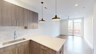 Located in Chicago's vibrant Uptown neighborhood at 5139 North Broadway, this modern one-bedroom, one-bathroom unit offers a thoughtfully designed open-concept layout. The combined living, dining, and kitchen area serves as the heart of the home, featuring warm hardwood floors, recessed lighting, and stylish pendant lights over a spacious kitchen island with light quartz countertops. The kitchen is equipped with stainless steel appliances, a gas range, subway tile backsplash, and rich wood cabinetry with sleek hardware. The living area opens directly onto a private patio balcony with striking views of the adjacent CTA Red Line elevated train platform, placing commuting conveniences just steps away. The bedroom is generously sized and includes a ceiling fan, direct balcony access through glass French doors, and multiple windows that bring in natural light and city views. Three closets provide ample storage throughout the unit. The full bathroom features a soaking tub with floor-to-ceiling white subway tile surround and a wood-accented vanity. A dedicated in-unit laundry closet with a stacked washer and dryer adds everyday convenience. Clean white walls, warm hardwood flooring, and modern finishes create a cohesive, contemporary ambiance throughout.