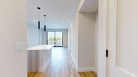 Located at 1556 NW 110th Ave in Sweetwater, FL, this thoughtfully designed unit is part of a modern multi-story residential building. The open-concept layout makes efficient use of the single-floor plan, with light wood-tone flooring running throughout the main living and kitchen areas, creating a warm and cohesive aesthetic.

The kitchen is a standout feature, equipped with full stainless steel appliances including a French door refrigerator, range, microwave, and dishwasher. Light wood cabinetry extends floor to ceiling, providing ample storage, while a central island with a crisp white quartz countertop serves as both a prep surface and casual gathering space. Sleek black pendant lights hang above the island, adding a contemporary accent.

The bathroom continues the modern design language with marble-look tile flooring and walls, a glass-enclosed walk-in shower, a wood-vanity with stone countertop, an illuminated mirror, and matte black fixtures throughout. A dedicated closet and hallway complete the functional layout.

A sliding glass door leads to a private balcony with black metal railings, offering open views of the surrounding Sweetwater skyline and lush Florida landscape. Recessed lighting and abundant natural light from large windows and the balcony access keep the interior bright and airy throughout.