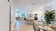 Located at 2300 SW 38th Ave in Ocala, Florida, this single-story 2-bedroom, 2-bathroom home offers a thoughtfully designed open-concept layout with clean, modern finishes. Light wood-style flooring flows through the main living areas, creating a bright and cohesive aesthetic. The kitchen is a standout feature, boasting white shaker cabinetry with black hardware, a white subway tile backsplash, stainless steel appliances, recessed and pendant lighting, and a central island with seating — ideal for casual dining. The kitchen opens seamlessly into the dining area and living room, where large windows and a glass door invite abundant natural light and outdoor views. The living room is accented by a ceiling fan and direct access to the exterior. The primary bedroom is generously sized, featuring plush carpet, a ceiling fan, and a bright window with outdoor views. The second bedroom offers a similarly comfortable retreat. Both bathrooms are finished with white cabinetry and modern fixtures; one includes a glass-enclosed walk-in shower. A dedicated laundry room with side-by-side washer and dryer adds everyday convenience. Two closets provide ample storage throughout the home.