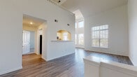 Located at 54 Republic Dr in Bloomfield, CT, this two-story home is defined by its dramatic double-height ceilings in the main living area, creating an expansive, airy atmosphere from the moment you enter. The main level features hardwood-style flooring throughout the open-concept layout, where the living area flows naturally toward a kitchen pass-through framed by an elegant arched opening. The kitchen is equipped with stainless steel appliances, including a gas range with over-the-range microwave, and features white cabinetry with light countertops. Large windows on the main level allow generous natural light to fill the space, with views of the surrounding neighborhood.

A staircase with a white balustrade leads to the upper level, where carpeted bedrooms offer a quieter, more private retreat. Bedrooms include closet space, with at least one room featuring a built-in shelving closet. A full bathroom on the upper level includes a vanity, toilet, and tub-shower combination with wood-style flooring. A dedicated laundry room with a full-size washer and dryer and overhead shelving adds everyday convenience to the upper floor.