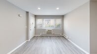 Located at 802 Main St in Toms River, NJ, this one-bedroom, one-bathroom residence offers a thoughtfully laid-out single-floor plan with a clean, neutral aesthetic throughout. The living room features light gray walls, modern luxury vinyl plank flooring, recessed lighting, and a window with outdoor views, creating a bright and welcoming atmosphere. A baseboard heating system and wall air conditioning unit ensure year-round comfort. The kitchen is outfitted with gray shaker-style cabinetry, sleek white quartz countertops, and a window that brings in natural light — a functional and stylish space for cooking and entertaining. The spacious primary bedroom is carpeted for warmth and comfort, and includes a ceiling fan with light fixture, a large double-door closet, and a sliding glass door that opens to natural light. The bathroom features a full tub-shower combination with large-format tile surround in neutral tones, brushed nickel fixtures, and a frosted window for privacy and ventilation. A connecting hallway links all rooms efficiently. Throughout the unit, the consistent gray-toned palette, white trim, and modern finishes lend a cohesive and contemporary feel to the space.