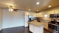 This single-floor residence offers a thoughtfully designed layout that balances functionality and comfort throughout. The open-concept kitchen and living area serves as the heart of the home, where rich dark hardwood flooring contrasts beautifully with light maple cabinetry. The kitchen is fully equipped with stainless steel appliances, including a French door refrigerator with ice maker, electric range, over-the-range microwave, and dishwasher. Granite countertops extend across the workspace and onto a central island, providing generous prep and dining space. Recessed lighting and a ceiling fan keep the area well-lit and comfortable. The living room features plush carpeting, large windows that invite natural light, and a door leading to the exterior. The bedrooms are carpeted and offer a calm, neutral palette, with one room featuring a wide multi-pane window with outdoor views. Two bathrooms serve the home; one includes a shower-tub combination with tile flooring and a vanity with storage, while the second features a single-sink vanity with a large mirror and vanity lighting. A dedicated laundry room with upper cabinetry and washer/dryer hookups rounds out this practical and well-finished space.