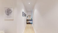 This thoughtfully designed 2-bedroom, 2-bathroom residence at 44 Hudson St in Yonkers, NY offers a contemporary living experience with refined finishes throughout. The open-plan kitchen and dining area showcases a sleek galley-style kitchen with two-tone cabinetry — warm wood lower cabinets paired with white upper cabinets — complemented by a white quartz countertop, marble-look tile flooring, and a full suite of stainless steel appliances. The bright living room is a standout space, anchored by dramatic floor-to-ceiling windows that frame sweeping views of the Yonkers skyline and the Hudson River beyond, filling the room with abundant natural light. Light hardwood flooring flows throughout the main living areas and hallway, which features recessed lighting and a clean, gallery-like aesthetic. Both bathrooms are finished with large-format gray stone tiles, floating wood vanities, illuminated mirrors, and soaking tub-shower combos. The primary bedroom offers generous proportions and its own set of floor-to-ceiling windows with outdoor views, while both bedrooms feature ample closet space. A dedicated laundry area and three closets add everyday convenience to this polished, modern home.