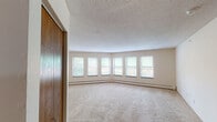Located at 10761 Smetana Rd in Minnetonka, Minnesota, this single-floor unit offers a practical and comfortable layout designed for everyday living. The living area is generously sized, featuring plush wall-to-wall carpeting, a textured ceiling, and a striking curved bank of windows that floods the space with natural light and provides pleasant outdoor views of the surrounding greenery. A pass-through window connects the living area to the kitchen, creating an open, communicative flow between the two spaces. The kitchen is equipped with oak cabinetry, white countertops, an electric range, and an over-the-range microwave, offering ample storage and functionality. The bedrooms are carpeted and well-proportioned, each featuring windows with outdoor views, baseboard heating, and individual wall-mounted air conditioning units for year-round climate control. Wood-toned closet doors add a warm accent throughout the unit. The bathrooms include tiled tub-and-shower combinations, with one bathroom featuring hardwood flooring, a wood-framed vanity mirror, and a white countertop. A dedicated in-unit laundry area with a stacked washer and dryer adds further convenience. Overall, the unit presents a clean, functional living environment in a well-established Minnetonka location.