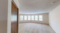Located at 10761 Smetana Rd in Minnetonka, Minnesota, this single-floor unit offers a practical and comfortable layout designed for everyday living. The living area is generously sized, featuring plush wall-to-wall carpeting, a textured ceiling, and a striking curved bank of windows that floods the space with natural light and provides pleasant outdoor views of the surrounding greenery. A pass-through window connects the living area to the kitchen, creating an open, communicative flow between the two spaces. The kitchen is equipped with oak cabinetry, white countertops, an electric range, and an over-the-range microwave, offering ample storage and functionality. The bedrooms are carpeted and well-proportioned, each featuring windows with outdoor views, baseboard heating, and individual wall-mounted air conditioning units for year-round climate control. Wood-toned closet doors add a warm accent throughout the unit. The bathrooms include tiled tub-and-shower combinations, with one bathroom featuring hardwood flooring, a wood-framed vanity mirror, and a white countertop. A dedicated in-unit laundry area with a stacked washer and dryer adds further convenience. Overall, the unit presents a clean, functional living environment in a well-established Minnetonka location.