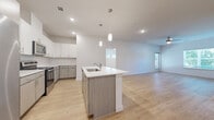 Located at 5900 S Congress Ave in Austin, TX, this modern 2-bedroom, 3-bathroom residence offers a thoughtfully designed open-concept layout finished with light wood flooring throughout. The combined kitchen and living area serves as the heart of the home, centered around a sleek kitchen island with a built-in sink and stylish pendant lighting overhead. White upper cabinetry contrasts with warm wood-toned lower cabinets, complemented by a classic subway tile backsplash and a full suite of stainless steel appliances, including a refrigerator, range, and microwave. The open living area extends naturally from the kitchen, bathed in natural light from large windows. Both bedrooms are generously proportioned, each featuring ceiling fans, windows with greenery views, and access to dedicated closets. The primary bedroom is notably spacious and accompanied by its own well-appointed bathroom. The three bathrooms are clean and modern, featuring wood-tone vanity cabinetry, white quartz countertops, and a tub-shower combination. Three closets provide ample storage, including a walk-in closet with wire shelving. A private balcony overlooks a landscaped courtyard, offering a relaxing outdoor retreat within this well-appointed Austin residence.