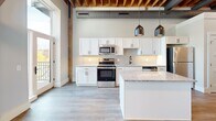 Located at 251 N Rose St in Kalamazoo, MI, this one-bedroom, one-bathroom unit blends industrial character with modern upgrades. The standout architectural feature is the exposed wood beam ceiling, visible throughout the unit and lending a warm, loft-inspired aesthetic that contrasts beautifully with the crisp white walls and light hardwood-style flooring.

The open-concept living, dining, and kitchen area serves as the heart of the unit. The kitchen is well-appointed with white shaker cabinetry, granite countertops, a tile backsplash, and a full suite of stainless steel appliances including a refrigerator, range, microwave, and dishwasher. A center island provides additional prep space and seating. Pendant lighting and large windows allow natural light to fill the space, enhancing its airy feel.

A hallway connects the main living area to the private bedroom, which features the same exposed beam ceiling and hardwood-style floors. Two closets offer generous storage. The bathroom is finished with a granite-topped white vanity, a walk-in tiled shower with matte black hardware, and wood-look flooring that ties the space together cohesively.

Black hardware accents are consistent throughout, adding a polished, contemporary touch to this thoughtfully designed urban residence.