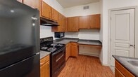 Located near the University of Texas at San Antonio on UTSA Blvd, this one-bedroom, two-bathroom unit offers a thoughtfully organized single-floor layout. The living area is bright and open, featuring plush carpeting, a ceiling fan with track lighting, and a sliding glass door that opens to a private balcony with outdoor views — allowing natural light to fill the space throughout the day.

The kitchen is well-equipped with warm wood cabinetry, dark granite-style countertops, hardwood-style flooring, and black appliances including a full-size refrigerator, electric range, dishwasher, and microwave. Ample cabinet and counter space makes it highly functional for everyday cooking.

The bedroom is comfortably sized, carpeted, and fitted with a ceiling fan. A large window provides natural light and exterior views. The room connects easily to the hallway and a dedicated closet for convenient storage.

The bathroom features hardwood-style flooring, a full tub-shower combo with tiled surround, a wood-tone vanity, and a light countertop. A dedicated laundry area with washer and dryer hookups adds everyday convenience. The unit's clean, neutral palette and practical layout make it a well-rounded living space.