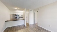 Located at 2445 64th Ave S in Saint Petersburg, FL, this one-bedroom, one-bathroom unit offers a practical and well-appointed single-floor layout. The living room greets you with wood-style plank flooring, neutral walls, and a large window fitted with blinds that frame views of the surrounding greenery, filling the space with natural light. A front entry door sits adjacent to the window, lending an open, airy feel to the room.

The kitchen is efficiently designed with crisp white shaker-style cabinetry, a dark countertop, and a full suite of stainless steel appliances including a refrigerator, electric range, and over-the-range microwave. A breakfast bar countertop provides additional prep and dining space, seamlessly connecting the kitchen to the living area.

The bedroom is carpeted for comfort, features a ceiling fan with a light fixture, and benefits from a window that brings in natural light and outdoor views. Two closets offer generous storage throughout the unit.

The bathroom is clean and functional, with wood-style flooring, white walls, and chrome hardware accents. A textured ceiling is consistent throughout the unit, adding a classic residential character. Overall, the space presents a bright, tidy, and functional layout well-suited for efficient everyday living.
