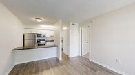 Located at 2445 64th Ave S in Saint Petersburg, FL, this one-bedroom, one-bathroom unit offers a practical and well-appointed single-floor layout. The living room greets you with wood-style plank flooring, neutral walls, and a large window fitted with blinds that frame views of the surrounding greenery, filling the space with natural light. A front entry door sits adjacent to the window, lending an open, airy feel to the room.

The kitchen is efficiently designed with crisp white shaker-style cabinetry, a dark countertop, and a full suite of stainless steel appliances including a refrigerator, electric range, and over-the-range microwave. A breakfast bar countertop provides additional prep and dining space, seamlessly connecting the kitchen to the living area.

The bedroom is carpeted for comfort, features a ceiling fan with a light fixture, and benefits from a window that brings in natural light and outdoor views. Two closets offer generous storage throughout the unit.

The bathroom is clean and functional, with wood-style flooring, white walls, and chrome hardware accents. A textured ceiling is consistent throughout the unit, adding a classic residential character. Overall, the space presents a bright, tidy, and functional layout well-suited for efficient everyday living.