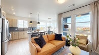 Located at 8355 E 32nd Ave in Denver's vibrant Central Park neighborhood, this well-appointed 2-bedroom, 2-bathroom residence offers a thoughtfully designed single-floor layout. A welcoming hallway adorned with artwork leads into the open-concept living, dining, and kitchen area — the heart of the home. Large windows wrap around the living and dining spaces, flooding the interior with natural light and framing scenic neighborhood views of the Colorado skyline and surrounding community. The kitchen features light wood cabinetry with black hardware accents, a slate tile backsplash, quartz countertops, stainless steel appliances, and a central island with pendant lighting overhead. Light-toned hardwood-style flooring runs throughout the main living areas, lending warmth and continuity. The primary bedroom is generously sized with plush carpeting, a ceiling fan, and a large window with open views, complemented by a spacious walk-in closet with wire shelving. A second closet with built-in shelving provides additional storage. Both bathrooms are finished with light wood vanities, black hardware, and tub-shower combinations. A dedicated laundry area adds everyday convenience. The clean, modern aesthetic and light-filled layout make this a comfortable and functional Denver residence.