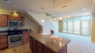 Located at 1142 Fawcett Ave, Unit 712 in Tacoma, Washington, this two-story residence offers a thoughtfully designed layout across two levels. The main floor centers around an open-concept living and kitchen area, where large windows flood the space with natural light. The well-appointed kitchen features rich cherry wood cabinetry, dark granite countertops, stainless steel appliances including a gas range, built-in microwave, and a French door refrigerator, all set atop warm hardwood flooring. A generous kitchen island with pendant lighting serves as a natural focal point and gathering space, flowing seamlessly into the carpeted living area. A staircase connects the main level to the upper floor, where carpeted bedrooms provide comfortable, quiet retreats. The upper level also includes a carpeted loft-style landing area. Two full bathrooms are finished with tile flooring, rich wood vanities, light countertops, and large mirrors. One bathroom features a walk-in shower, while the other includes a full tub-shower combo. A carpeted hallway with wall sconce lighting connects the upper-level rooms. Throughout, warm neutral tones and consistent finishes create a cohesive and inviting atmosphere.
