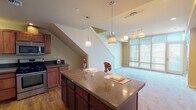 Located at 1142 Fawcett Ave, Unit 712 in Tacoma, Washington, this two-story residence offers a thoughtfully designed layout across two levels. The main floor centers around an open-concept living and kitchen area, where large windows flood the space with natural light. The well-appointed kitchen features rich cherry wood cabinetry, dark granite countertops, stainless steel appliances including a gas range, built-in microwave, and a French door refrigerator, all set atop warm hardwood flooring. A generous kitchen island with pendant lighting serves as a natural focal point and gathering space, flowing seamlessly into the carpeted living area. A staircase connects the main level to the upper floor, where carpeted bedrooms provide comfortable, quiet retreats. The upper level also includes a carpeted loft-style landing area. Two full bathrooms are finished with tile flooring, rich wood vanities, light countertops, and large mirrors. One bathroom features a walk-in shower, while the other includes a full tub-shower combo. A carpeted hallway with wall sconce lighting connects the upper-level rooms. Throughout, warm neutral tones and consistent finishes create a cohesive and inviting atmosphere.