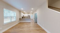This well-designed two-story home showcases a thoughtful layout and modern finishes throughout. The main level opens into a bright, open-concept living and kitchen area finished with light hardwood flooring and recessed lighting. The kitchen is a standout feature, equipped with crisp white shaker cabinetry extending to the ceiling for ample storage, granite countertops, and a full suite of stainless steel appliances including a refrigerator, range, and microwave. A peninsula with a built-in sink provides additional workspace and casual seating, seamlessly connecting the kitchen to the living area. Natural light flows in through multiple windows fitted with blinds. A private water closet and additional utility access are conveniently located on this floor. The upper level features generously sized bedrooms carpeted in neutral tones, each equipped with ceiling fans and windows that invite natural light and outdoor views. The bathrooms continue the home's consistent design language, featuring white vanity cabinetry, granite countertops, large mirrors, and hardwood-style flooring. Neutral wall tones and clean white trim carry throughout, creating a cohesive and inviting atmosphere across both floors.