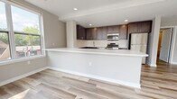Located on E Main St in Bound Brook, NJ, this single-floor residence showcases a thoughtfully designed open-concept layout with contemporary finishes throughout. Light-toned hardwood flooring flows seamlessly across the living areas, enhancing the bright and airy ambiance created by recessed lighting and multiple windows.

The kitchen is a standout feature, outfitted with rich dark-brown cabinetry, a crisp white quartz peninsula, subway tile backsplash, and a full suite of stainless steel appliances including a gas range, built-in microwave, and refrigerator. The peninsula-style layout opens toward the main living area, making it ideal for entertaining.

The living space benefits from a large bay-style window arrangement that invites generous natural light and offers views of the surrounding neighborhood. The bedroom features a tray ceiling detail, a dedicated closet, and a window with outdoor views, complemented by warm hardwood flooring.

The bathrooms are finished with elegant marble-patterned tile surrounds on the tub-shower combinations, neutral floor tiles, and in the primary bath, navy blue cabinetry that adds a bold, modern accent. Neutral warm-gray walls tie the entire space together, delivering a clean and contemporary residential environment.