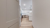 Located in Avondale, Arizona, this single-story 2-bedroom, 2-bathroom home offers a clean, contemporary design with a bright, neutral palette throughout. The open kitchen serves as the centerpiece of the home, featuring a large granite-topped island, two-tone cabinetry with white upper cabinets and warm wood-toned lower cabinets, a glossy white tile backsplash, and a full suite of stainless steel appliances including a refrigerator with ice maker, range, microwave, and dishwasher. Globe pendant lights add a modern touch above the island. Light wood-look flooring flows through the main living and kitchen areas, lending warmth and continuity to the space. The primary bedroom is generously sized with plush carpet, a ceiling fan, and a window that brings in natural light. Its en-suite bathroom offers a dual-sink vanity with granite countertops, warm wood cabinetry, and access to a spacious walk-in closet with built-in shelving. A second carpeted bedroom and a full second bathroom with a matching granite vanity round out the layout. Two hallways connect the rooms efficiently, and dedicated closets provide ample storage throughout the home.