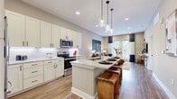 This thoughtfully designed one-bedroom, one-bathroom residence in Smyrna, Tennessee offers a cohesive open-concept layout that maximizes every square foot. The kitchen is a standout feature, showcasing crisp white shaker cabinetry, quartz countertops with a classic subway tile backsplash, stainless steel appliances, and a center island with bar seating illuminated by elegant pendant lighting — ideal for both cooking and casual dining. The kitchen flows seamlessly into the living room, where wood-look flooring, recessed lighting, and large glass doors invite abundant natural light and outdoor views, creating a warm and inviting atmosphere. The generously sized bedroom accommodates a king bed comfortably and is complemented by multiple windows with natural light, neutral tones, and a ceiling fan. The bathroom features white cabinetry, quartz countertops, a large framed mirror, and tile flooring, lending a clean, modern aesthetic. A dedicated laundry area with a full-size washer and dryer adds everyday convenience. Throughout the home, wood-look flooring, neutral wall tones, and matte black hardware create a cohesive, contemporary feel that is both stylish and functional.