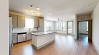 This thoughtfully designed one-bedroom, one-bathroom unit offers a bright and functional open-concept layout that seamlessly connects the kitchen and living area. Light wood-look flooring runs throughout, lending a clean and cohesive aesthetic across every room.

The kitchen is a standout feature, boasting a central granite-topped island, crisp grey shaker cabinetry, a white tile backsplash, and a full suite of stainless steel appliances including a refrigerator with ice maker, range, microwave, and dishwasher. Track lighting illuminates the space, while a window over the sink brings in natural light.

The living area is open and airy, benefiting from multiple large windows and a ceiling fan that enhance both comfort and brightness. A glass door provides access to the exterior, furthering the sense of openness.

The bedroom is a comfortable and well-lit retreat, featuring a ceiling fan, a sizable window with outdoor views of lush greenery, and generous proportions. The full bathroom is elegantly finished with a granite-topped vanity, a soaking tub, a separate glass-enclosed shower, and wood-look tile flooring, with an adjacent walk-in closet offering ample storage.

Completing the unit is a dedicated laundry room with a full-size washer and dryer and overhead shelving for added convenience.