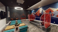 This single-floor recreation lounge is designed around an immersive ski and mountain theme, combining active amenities with comfortable social seating. The centerpiece of the space is a professional ski simulator, flanked by bold red safety netting and set against a dramatic feature wall mural depicting stylized mountain peaks, pine trees, and a skier in motion rendered in deep navy, orange, and white tones. A repurposed red ski chairlift serves as a unique decorative and functional seating element, reinforcing the alpine aesthetic throughout. The lounge area is anchored by teal upholstered chairs arranged around a slatted wood coffee table, providing a comfortable gathering space ideal for relaxing before or after activity. Two large wall-mounted flat-screen televisions face the seating area, complemented by vintage Colorado ski travel posters that add character to the lighter accent wall. Dark charcoal walls and a dark ceiling create a moody, enveloping atmosphere, while a bold circular ring pendant light serves as a dramatic overhead focal point. Recessed ceiling lighting provides additional illumination over the simulator area. Textured, patterned carpet anchors the space and adds warmth underfoot. Decorative bead strands adorn the darker walls, adding subtle artistic detail to this dynamic, well-appointed recreation room.