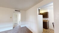 This efficiently designed 2-bedroom, 1-bathroom single-floor unit offers a thoughtfully organized layout that maximizes functionality. The living room features neutral carpet flooring, a window with blinds that allows natural light to filter in, and a textured ceiling, creating a simple and clean atmosphere. Adjacent to the living room, the dining area accommodates a standard dining set and includes a window that brightens the space. The kitchen is equipped with dark wood cabinetry, granite-style laminate countertops, a double stainless steel sink, and tile flooring, offering ample storage and counter space in a compact galley-style arrangement. The primary bedroom includes a ceiling fan with light fixture, carpeted flooring, a window with blinds, and a textured ceiling. The second bedroom, also carpeted, provides a versatile space suitable for use as a guest room or home office. The shared full bathroom features tile flooring, a tub-shower combo with white tile surround, a single vanity with white cabinetry, and a toilet. The unit also includes a hallway, entrance area, and a closet for additional storage. Central HVAC vents are visible throughout, ensuring year-round climate control.