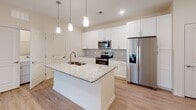 Located at 625 Maple Dr in Greer, SC, this single-floor residence is designed with a clean, modern aesthetic and a functional open layout. The kitchen serves as a central highlight, featuring white shaker-style cabinetry, granite countertops, stainless steel appliances including a refrigerator, electric range, and microwave, and a large kitchen island with a built-in sink illuminated by stylish pendant lighting. Light wood-look flooring flows throughout the kitchen and living areas, reinforcing a bright, cohesive feel.

The open-concept living area extends naturally from the kitchen, with recessed lighting, neutral walls, and access to natural light through glass doors leading to the outdoors. Multiple bedrooms are finished with plush carpeting, ceiling fans, and windows that bring in additional natural light.

The bathrooms are well-appointed, each featuring granite-topped vanities with white cabinetry. The primary bathroom includes a long vanity with ample counter space and access to a walk-in closet with built-in shelving. A secondary bathroom offers a full tub-shower combination with a curved curtain rod. Throughout, the space maintains a consistent, neutral palette that creates a clean and welcoming atmosphere.