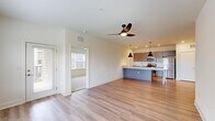 Located on Old Lynchburg Road in Charlottesville, VA, this well-designed 2-bedroom, 2-bathroom residence offers a thoughtful single-floor layout with modern finishes throughout. The open-concept living and kitchen area serves as the heart of the home, featuring light hardwood-style flooring, a ceiling fan with integrated lighting, and seamless flow between spaces. The kitchen is a standout, boasting a large island with a striking marble-patterned stone countertop, an undermount sink, and stylish dual pendant black lights. Taupe-toned cabinetry pairs elegantly with stainless steel appliances, including a refrigerator, range, and microwave. A dishwasher is neatly integrated beneath the extended countertop. Both bedrooms are carpeted and fitted with ceiling fans, offering a comfortable and quiet retreat. The primary bedroom is generously sized and includes direct access to a private en-suite bathroom, which features a stone-topped vanity with gray cabinetry, large-format tile flooring, and a glass-enclosed shower. The second bathroom includes a full tub-shower combination. Natural light flows through multiple windows with outdoor greenery views, enhancing the bright, airy ambiance of the entire residence.