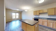 Located on the fourth floor at 100 2nd Ave in downtown Des Moines, Iowa, this 2-bedroom, 2-bathroom residence offers a well-organized single-level layout. The open-concept kitchen and living area serves as the heart of the unit, featuring light maple cabinetry, dark countertops, a center island, and black appliances including a refrigerator and range. Durable hardwood-style flooring runs throughout the main living and kitchen areas, complemented by flush-mount ceiling fixtures that provide consistent illumination.

Both bedrooms are comfortably sized and finished with plush wall-to-wall carpeting. Each room is brightened by windows overlooking the surrounding urban streetscape, allowing natural light to fill the space throughout the day. The generously proportioned primary bedroom provides ample room for furnishings.

The two bathrooms are finished with hardwood-style flooring, warm wood-toned vanities with light countertops, and large mirrors. One bathroom includes a full tub-shower combination, while the second features accessibility-friendly grab bars and a open layout. Neutral warm-toned walls throughout the unit create a cohesive, move-in-ready aesthetic suited for a variety of interior styles.