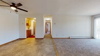 This single-floor unit at High Ridge Trail in Fitchburg, Wisconsin, offers a straightforward, functional layout designed for comfortable everyday living. The living area is generously sized, featuring neutral carpet underfoot and tile flooring in the adjoining dining or entry zone. A sliding glass door floods the space with natural light and provides outdoor access, while a wall-mounted air conditioning unit and baseboard heating ensure year-round climate control.

The kitchen is positioned off the main living area and features warm-toned wood cabinetry, a white appliance suite, and tile flooring, creating a practical cooking space. A central hallway connects the main living areas to the private rooms, maintaining a clear and organized flow throughout the unit.

The bedroom is a well-proportioned, carpeted space with two windows that admit abundant natural light and views of greenery outside. A standout feature is the spacious walk-in closet, fitted with floor-to-ceiling wire shelving on multiple walls, offering extensive storage and organization options.

The bathroom includes a wood-toned vanity with an integrated sink, a mirrored medicine cabinet, and a tub-shower combination. Wood-look flooring and track lighting complete the room. Overall, the unit presents a clean, practical design well-suited to daily living.