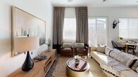 This well-appointed single-floor residence offers a cohesive blend of modern and organic design elements throughout its thoughtfully laid-out spaces. The living room is bright and welcoming, featuring a ceiling fan, large windows with patterned drapes, and a sliding glass door that allows natural light to fill the room. The space is anchored by a neutral palette, complemented by warm wood tones and layered textures. The kitchen is equipped with stainless steel appliances, including a range, built-in microwave, dishwasher, and a side-by-side refrigerator. Rich wood-toned cabinetry extends to the ceiling, offering ample storage, while clean white countertops provide generous prep space. A cozy dining nook with a round table sits adjacent, bathed in natural light from large windows. The primary bedroom is serene and spacious, featuring soft carpet, elegant bedside lighting, and a bold decorative wall piece as a focal point. A secondary bedroom offers a bright, airy atmosphere with natural light and tasteful artwork. The bathroom includes a dual-sink vanity with wood cabinetry, a tub-shower combination, and a window for natural light. A dedicated office area with a herringbone-patterned area rug and built-in desk completes this versatile and inviting home.