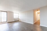 Located at 136 Bay St in downtown Hamilton, Ontario, this 2-bedroom, 1-bathroom unit offers a well-organized single-floor layout designed for comfortable everyday living. Warm hardwood flooring runs throughout the main living and bedroom areas, lending a cohesive and inviting feel to the space.

The living room is generously proportioned, bathed in natural light through large floor-to-ceiling windows and a sliding glass door that opens to a balcony overlooking the Hamilton cityscape. Baseboard heating units line the perimeter, ensuring year-round comfort.

The kitchen follows a galley-style configuration, featuring white shaker cabinetry, subway tile backsplash, dark countertops, and a stainless steel double sink. Tile flooring and ample upper and lower cabinet storage make this a highly functional cooking space. The kitchen connects directly to the unit's entryway.

The primary bedroom offers a comfortable footprint with a window framing city views and hardwood flooring. The second bedroom is a well-sized, bright room with hardwood floors and closet access.

The full bathroom is finished with white subway tile in a classic brick pattern, accented by a grey tile band, and includes a soaker tub with shower, chrome fixtures, and a safety grab bar. The overall aesthetic throughout is clean, neutral, and move-in ready.