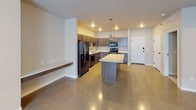 This 1-bedroom, 1-bathroom unit offers a thoughtfully designed, open-concept layout that blends modern finishes with industrial-inspired elements. Polished aggregate concrete floors run throughout the main living areas, reflecting light and lending a sleek, contemporary feel to the space.

The kitchen is a standout feature, equipped with dark wood cabinetry, stainless steel appliances — including a french door refrigerator, range, microwave, and dishwasher — and crisp white countertops. A generously sized center island provides additional prep and seating space, while two pendant lights hang above, adding warmth to the area. A built-in floating shelf along the adjacent wall offers a practical and stylish touch. Recessed lighting illuminates the kitchen, which flows seamlessly into the open living area.

The bedroom is a comfortable, well-proportioned room featuring the same polished aggregate flooring, exposed HVAC ductwork along the upper perimeter that nods to the unit's industrial aesthetic, and a window fitted with roller shades that allows natural light to filter in softly.

The bathroom is finished with wood-look luxury vinyl plank flooring, dark cabinetry paired with a white countertop vanity, a lighted mirror, and a full tub-shower combination. The overall design is clean, cohesive, and move-in ready.