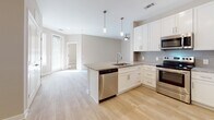 Located in Henrico, Virginia, this well-appointed single-floor residence offers a clean, contemporary design throughout. The open-concept layout connects the kitchen and living area seamlessly, creating a bright and airy atmosphere. Light wood-tone flooring extends across the main living spaces and bedrooms, complementing the neutral warm-beige wall tones that are consistent throughout the home.

The kitchen is a standout feature, boasting white shaker-style cabinetry, granite countertops, a subway tile backsplash, and a full suite of stainless steel appliances including a refrigerator, range, microwave, and dishwasher. Pendant lighting above the peninsula adds a polished finishing touch, while the open sightline into the living area makes the space feel expansive and connected.

The bedrooms are well-sized, each featuring ceiling fans, natural light from multiple windows with blinds, and easy access to closet storage — including a walk-in closet in one room. Bathrooms are finished with marble-style tile flooring, granite-topped white vanities, and tub/shower combinations, while the primary bath includes a separate glass-enclosed shower. The overall ambiance is bright, clean, and move-in ready.